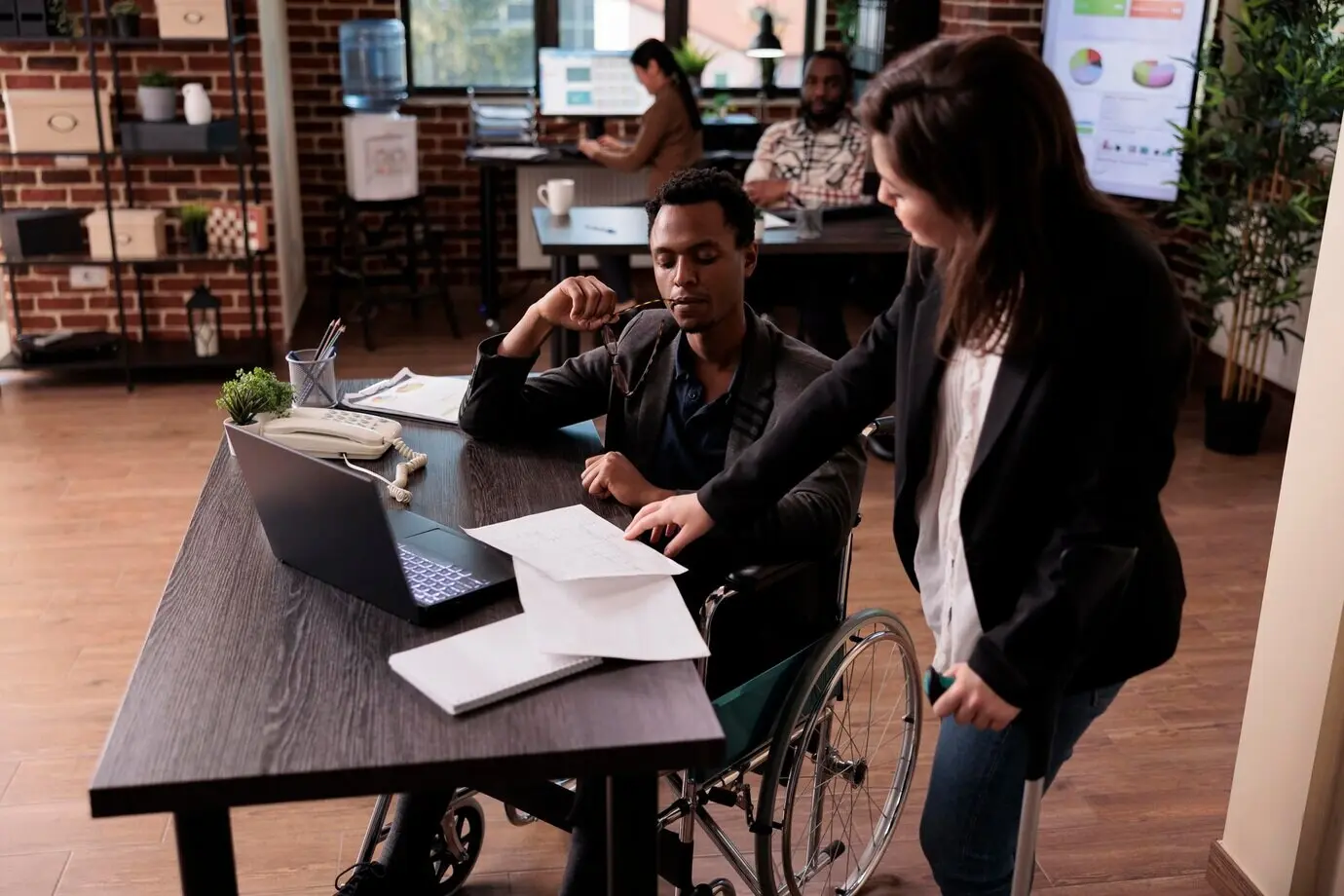 Menschen mit einer körperlichen Beeinträchtigung arbeiten im Startup-Büro im Team und gehen am Arbeitsplatz mit einer chronischen Behinderung um. Geschäftspartner mit Beeinträchtigung arbeiten an einem Projekt und nutzen Rollstuhl und Krücken.