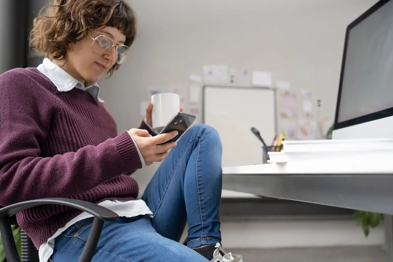 Junge Designerin, die ihr Smartphone überprüft.